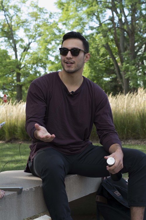 man outside on bench gesturing with hand