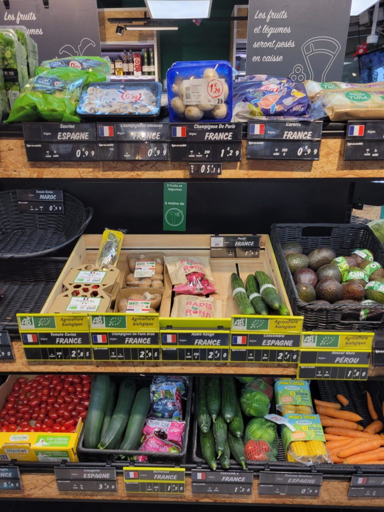 An image of a grocery shop's fresh produce section containing potatoes, gourds, avocados, tomatoes, etc.  