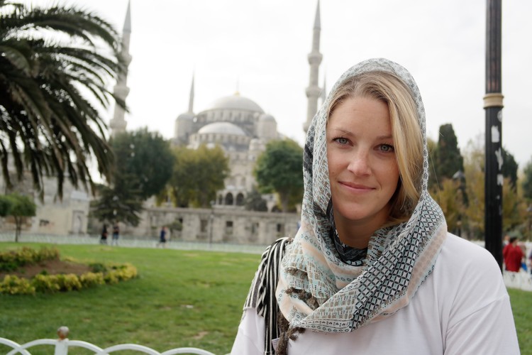 woman in headscarf in front of building with Minarets