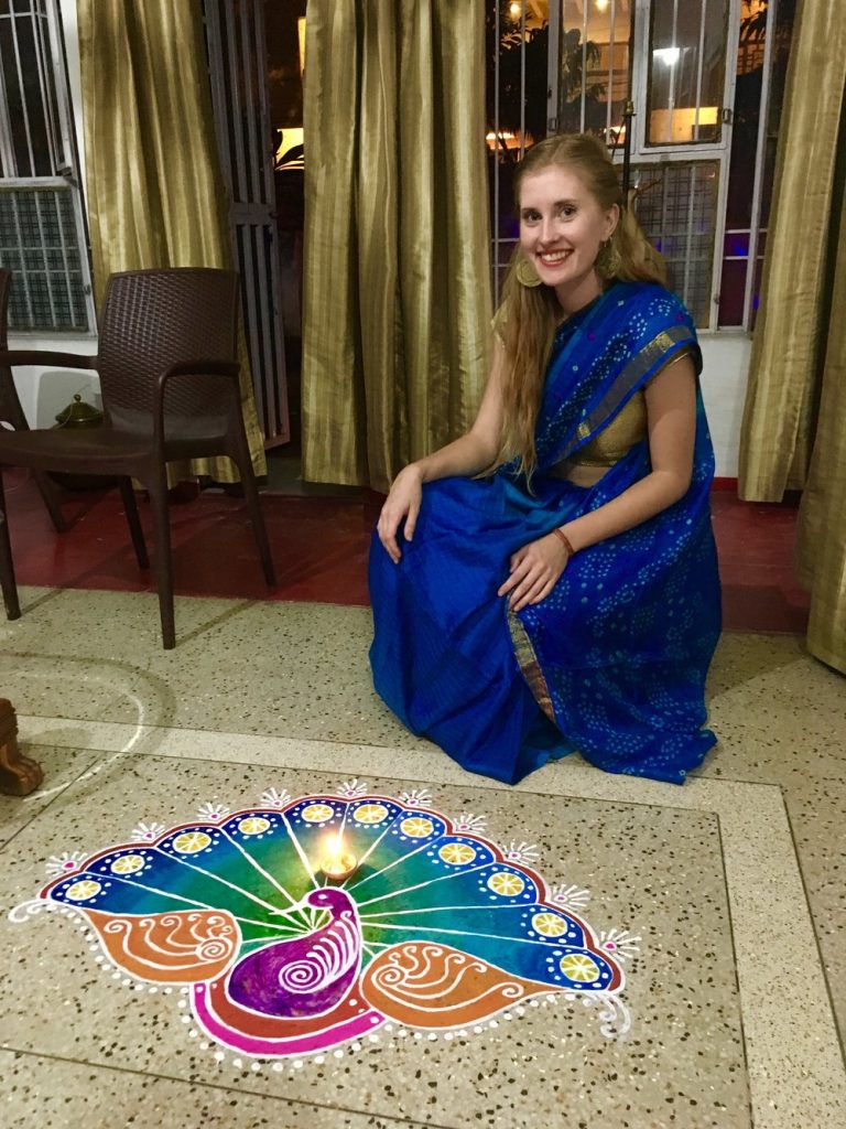 woman in sari next to peacock art