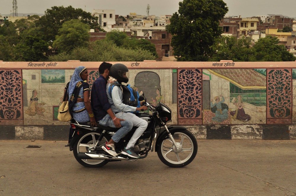 three people riding one motorcycle