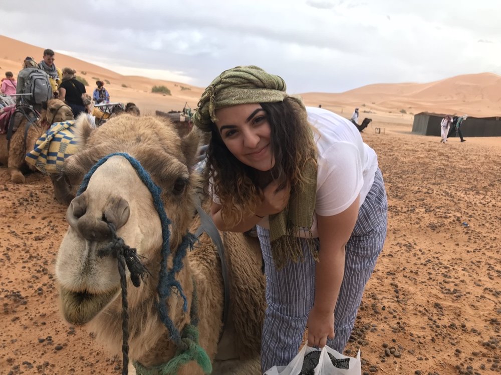 woman standing next to camel