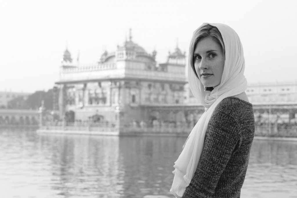 woman in headscarf in front of water and cool building