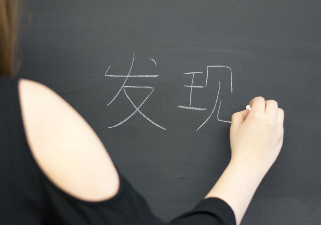 A woman is writing Chinese characters on a chalkboard. 