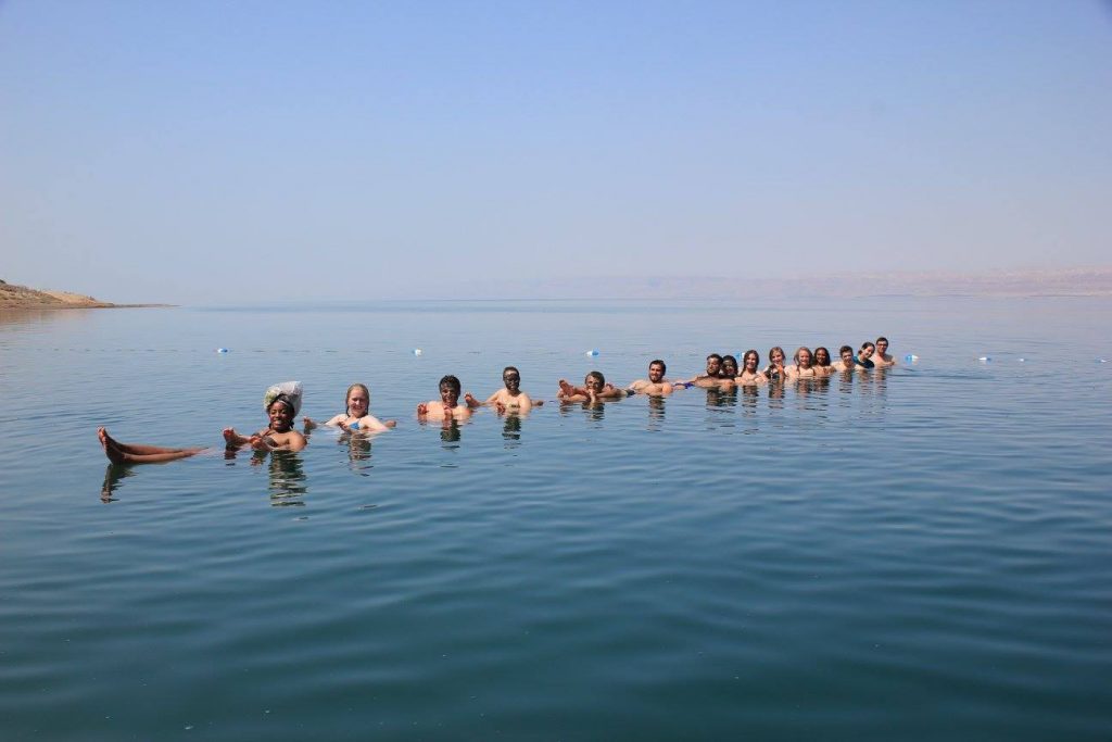 A group of people in a line float in an ocean.
