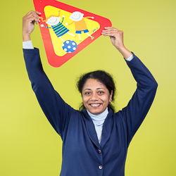 A woman smiles while holding a poster with children playing on it.