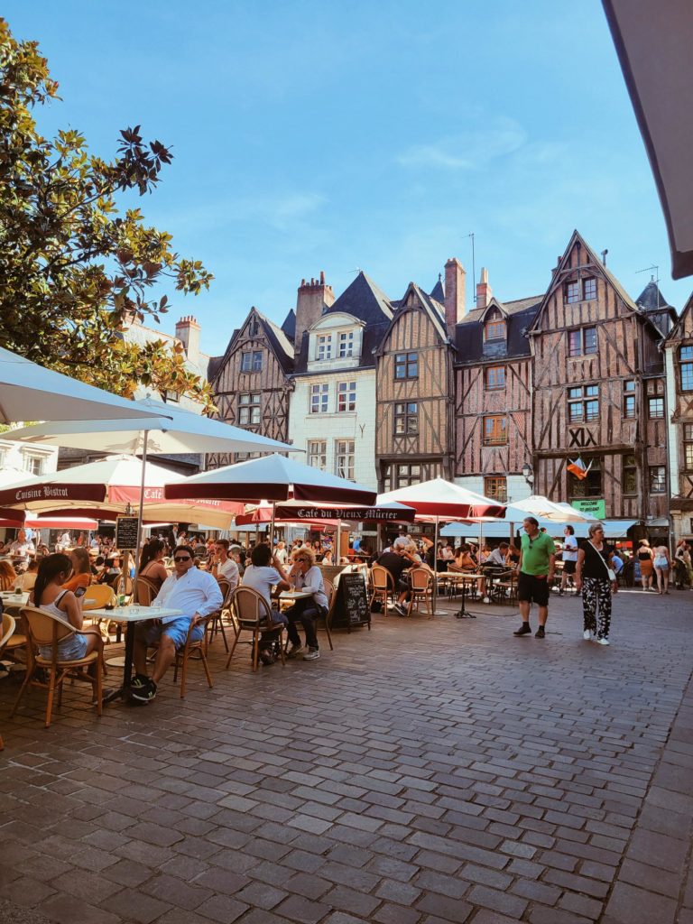 An image of a sitting place outside of a medieval building where people are sitting and probably waiting for food. 