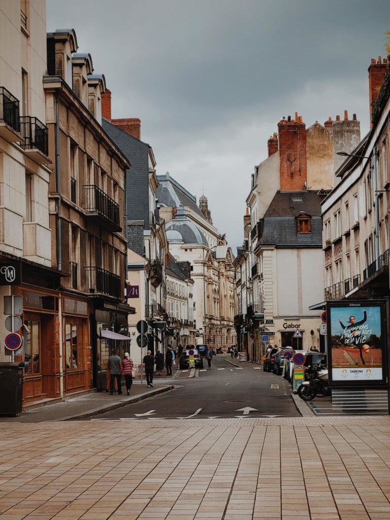 A local street in the city of paris with people walking on the sidewalk.  